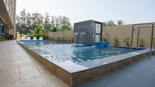 Image of a outdoor swimming pool with trees in the background at Pride Elite Daman.