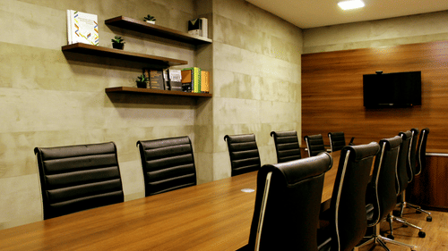 Executive boardroom with wooden table and ergonomic leather chairs.