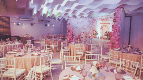 An elegant event space decorated predominantly in pink hues, with tables set for a celebration.