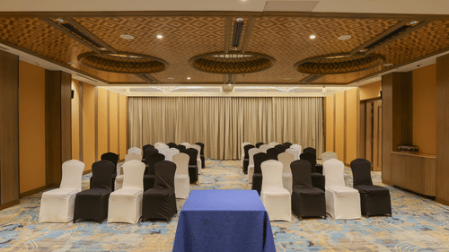 A room with rows of chairs facing a table, possibly set up for a meeting or event - Pride Premier Pune