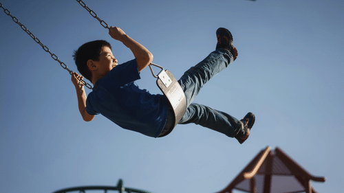 A child enjoying a swing mid-air on a sunny day.