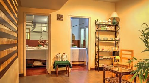 Image of interior of the Golden Glory Spa at Pride Sun Village Resort and Spa in Goa featuring essential oils stacked up on the shelves next to the doorway to the spa room with spa beds