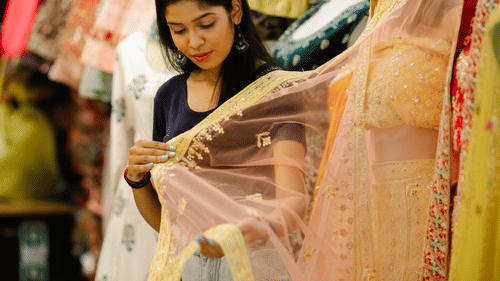 a woman looking at a fancy see through dupatta while shopping in a shop