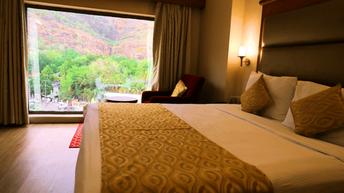 Bedroom with bed, seating area, and view.