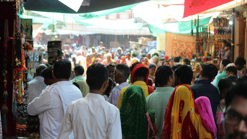 Bust street scene in India, with people walking , cars driving and buildings lining the road