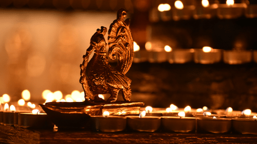 Ornate brass lamp surrounded by rows of glowing diyas in a festive setting
