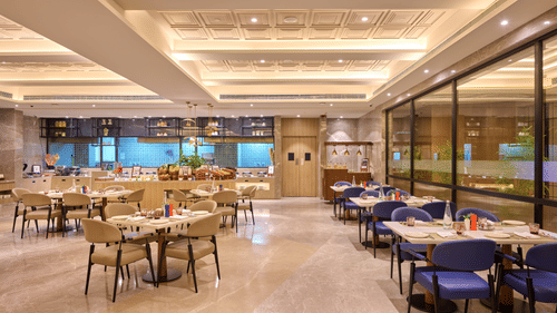 Indoor restaurant at Riviera Sarovar Portico, Pathankot showcasing contemporary seating, warm lighting and a refined space for all day dining.