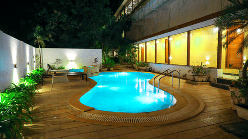 An overview of the swimming pool with lights on in the night - Rosetum Anjuna.