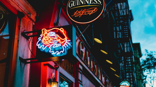 A neon sign of a man with a beard, and a Guinness sign.