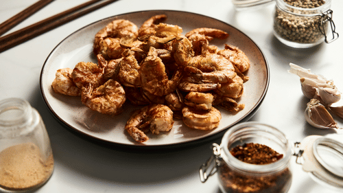 A close up shot of a plate with prawns with other condiments next to it