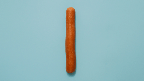 An aerial view of a single sausage kept on a a shade of blue coloured table