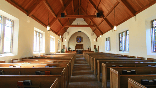interior of the church with seats, the altar in view and wooden roof