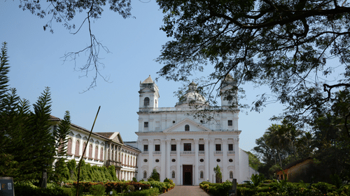Facade image of Church of St. Cajetan with another building on the side and a tree cover in the foreground