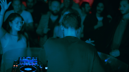 A DJ using his turntable at a party with a crowd dancing in front of him