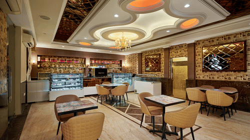 tables and chairs beside the display counter at our cafe - Royal Kingdom Sarovar Portico, Pilibhit