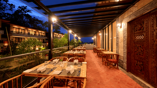 Outdoor dining setup on a covered patio with warm evening lighting - Royal Tulip, Chitwan