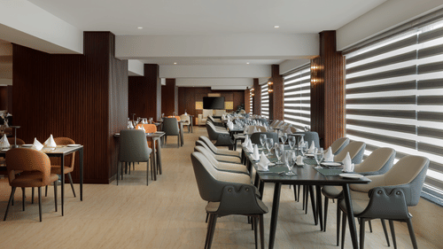 The bright and spacious dining area at Royal Tulip, Kathmandu, with tables neatly arranged for meals.