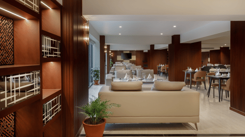 The elegant dining area at Royal Tulip, Kathmandu, with a comfortable waiting lounge and polished wooden shelves.