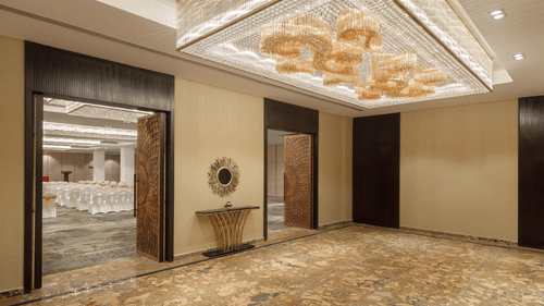 The entrance to a grand banquet hall at Royal Tulip, Kathmandu, featuring ornate doors and a stylish chandelier.