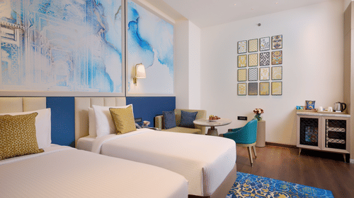 An image with twin beds in the foreground and cosy furniture to the back - Sarovar Premiere, Amritsar