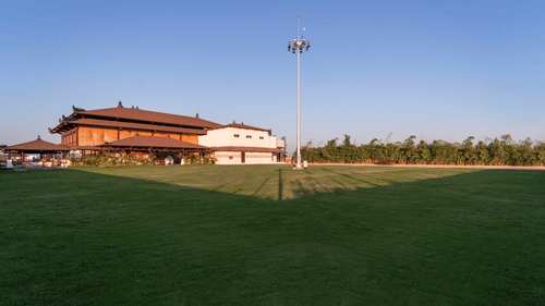 Lawn area with a light pole and building in the background - Shyama Sarovar Portico Orai