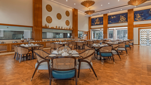 Seating arrangements with paintings on the wall at the in-house restaurant - Shyama Sarovar Portico Orai