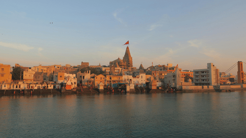 A panoramic view of a densely built coastal or riverside city skyline under a clear blue sky.