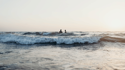 two people swimming at a beach
