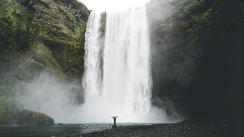An image of a man posing in front of a deep waterfall