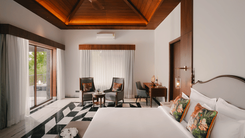 Bedroom at The Ananta Udaipur with a king bed and balcony overlooking the greenery.