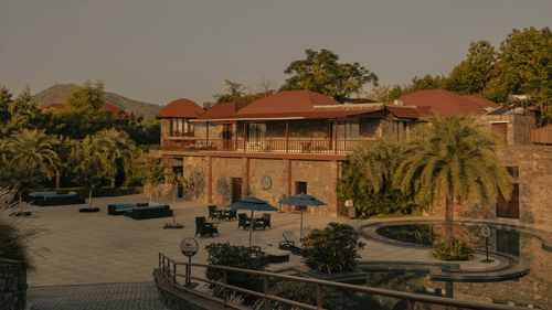  An aerial view of a resort with multiple buildings, swimming pools, and surrounding landscape.