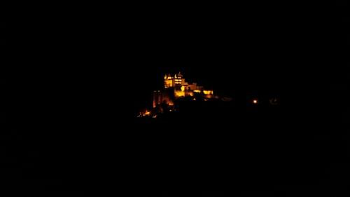 A far out view of Sajjangarh Monsoon Palace with lights on in the night