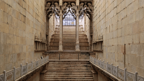 Steps leading up with columns having intricate carvings inside a building in Bundi