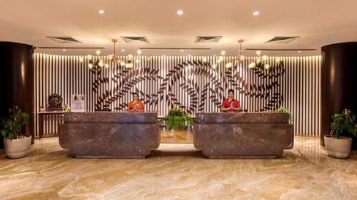 Two receptionists at the lobby of Pride Premier Nagpur desk doing namaste which is a way to greet guests.