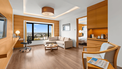 Side view of the Club Suite living room with a cozy sofa in the corner and a view from the window at The Residency Towers Coimbatore