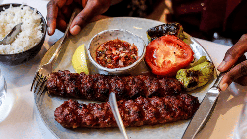 A top down view of a plate of kebabs served to a diner with sides and cutlery on the plate at The Retreat Hotel and Convention Centre