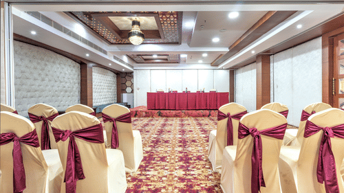 A big banquet hall  with multiple decorated  chairs - The Saibaba Hotel