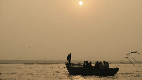 A solitary boat with many people on it travelling in the Ganges river. 