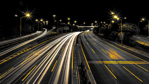 a far out view of a highway with time lapse setting where the headlights show up as lines