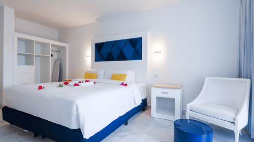 A bedroom featuring kind size bed, a wardrobe, bedside lamps and and a table & chair set at The Soco House.