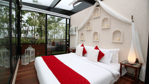 A bed beautifully set up in an open-air space, surrounded by an enchanting view with nature and sky above