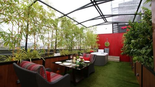 An image of a cafe featuring chairs and tables surrounded by plants and glass ceilings  | Theory9 - Premium Service Apartments, Bandra