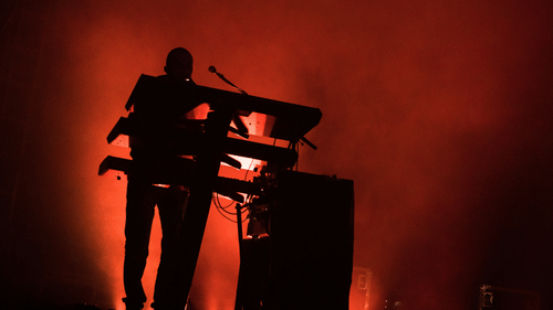 The silhouette of a musician performing on stage with a keyboard