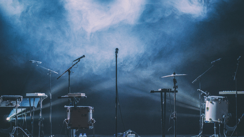 An empty concert stage with drums, microphones, and lights