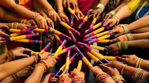 Many hands holding colourful sticks arranged in a circular pattern.