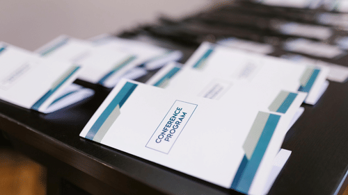 The image shows a stack of brochures or pamphlets on a table. 