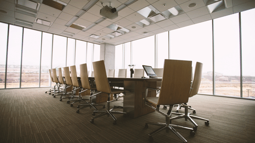 a rectangle table with chairs and floor to ceiling windows covering the walls