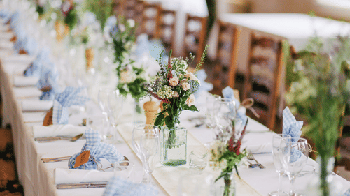 Dining table at a function well decorated with vases, glasses and cutlery folded with the napkins
