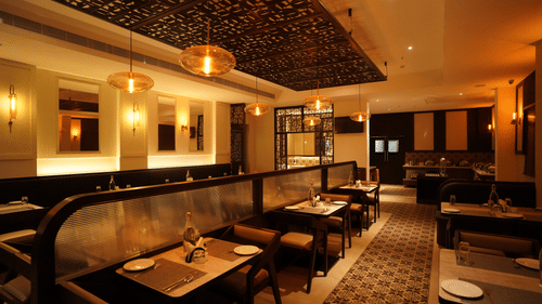 Restaurant dining area at V FIVE HOTEL with tables, chairs, plates, glasses, water bottles, pendant lights, wall mirrors, patterned floor tiles, and a buffet counter in the background.