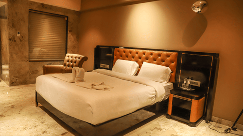 A king bed with cushioned headboard and side tables next to the bed inside one of the rooms at VITS Nanded Hotel